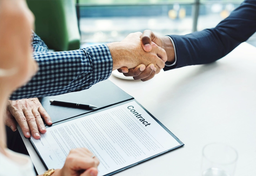 AIBN Agreement Structuring & Negotiation, two business people shaking hands over a signed contract.