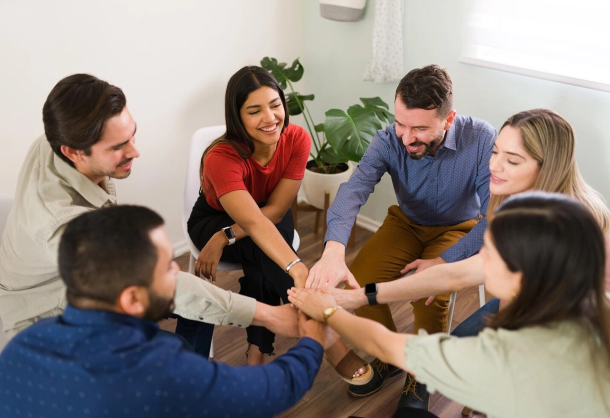 A group of diverse people putting their hands together in a circle, showing AIBN's community engagement.