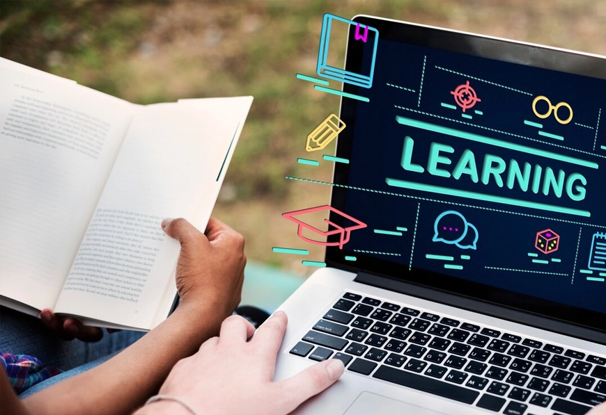 A person using a laptop with "Learning" on the screen, representing AIBN's Business Training Programs and continuous development.