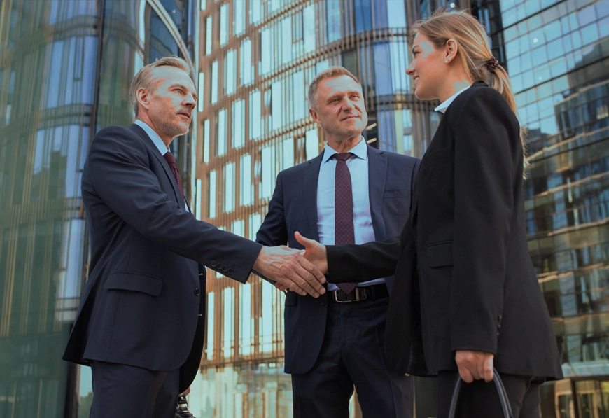 AIBN professionals shaking hands outside glass office, symbolizing formal partnership and strategic collaboration.
