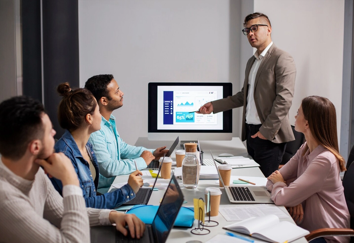 Professional team meeting with a man presenting on a screen. AIBN business consulting and training.