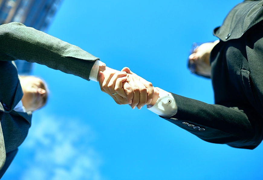 Handshake under sky showing AIBN strategic alliance services.