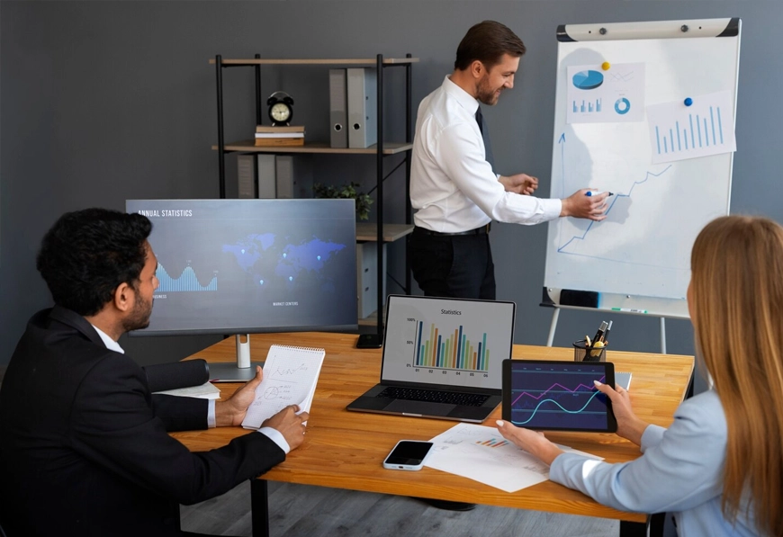 AIBN team reviewing charts and global data in office meeting, symbolizing analysis and planning.