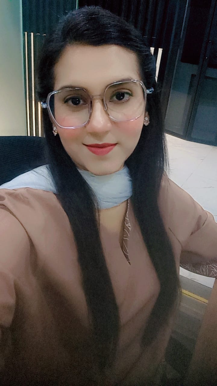Woman in glasses and scarf smiling indoors showing ABIN team presence and professional warmth.