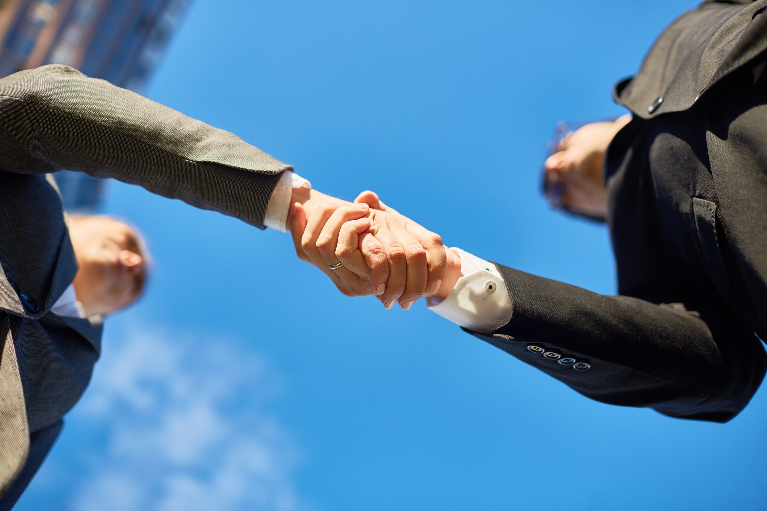 AIBN business partners shaking hands with a blue sky background.